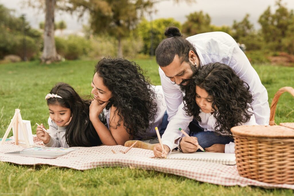 Happy indian family painting together at park - Family, parents and children love