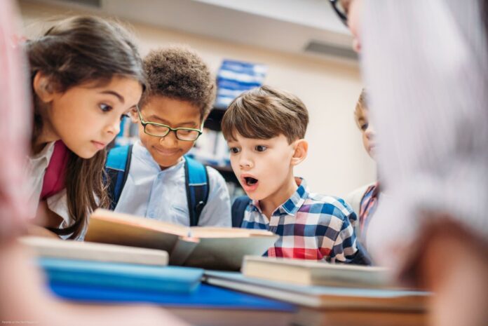 shocked little children looking at book in library