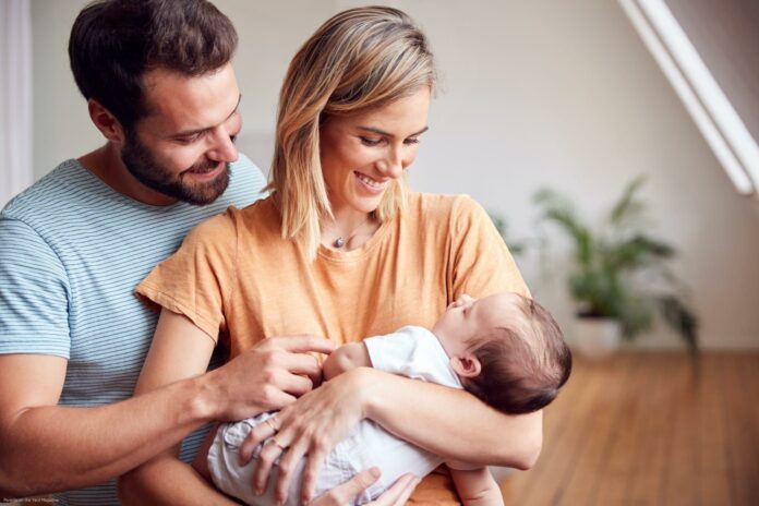 Loving Parents Holding Newborn Baby At Home In Loft Apartment Loving Parents Holding Newborn Baby At Home In Loft Apartment