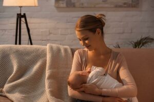 smiling young mother breastfeeding baby at night