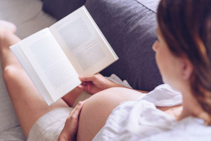 Pregnant woman reading a book at her home. Pregnant woman reading a book at her home.