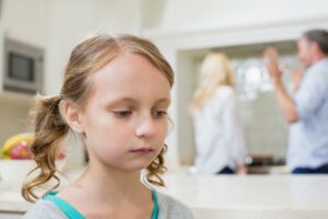 Sad girl listening to her parents arguing