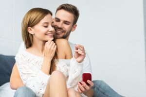 handsome man doing marriage proposal to smiling and attractive woman