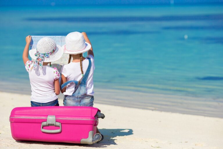 5 Tips For Traveling With Kids – Successfully! Little girls with big suitcase and map at tropical beach