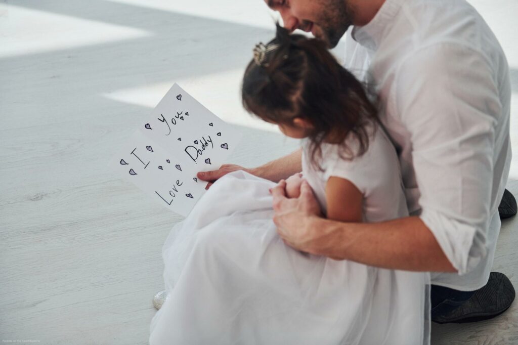 Happy father's day. Daughter makes surprise for dad by giving postcard with heart