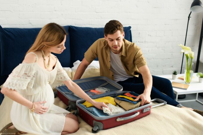 pregnant woman and husband packing travel bag for vacation pregnant woman and husband packing travel bag for vacation