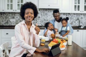 Woman working on tablet while husband playing with kids