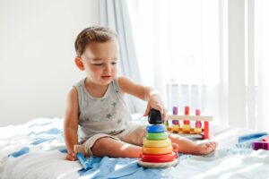 Baby playing with toy pyramid stacking blocks at home. Early education, kids brain development