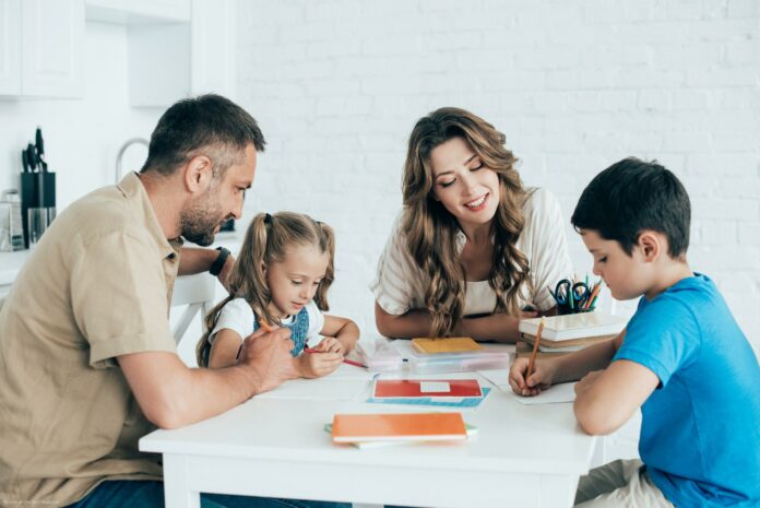 parents helping children with homework at table at home parents helping children with homework at table at home