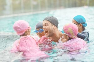 Cheerful professional instructor having fun with kids in the water