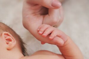 mother holds hand of newborn baby